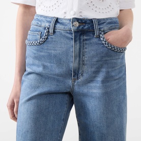 Model wearing Paige Straight Jeans in Encino blue denim with woven belt detail at waistband, styled with white broderie top.