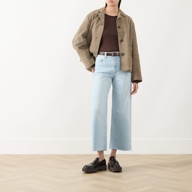 Model wearing Paige Motif straight jeans in light blue denim, styled with a tan jacket, brown top, belt, and black loafers.