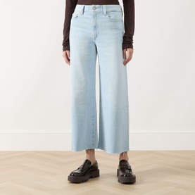 Model wearing Paige Straight Jeans in Motif light blue wide-leg denim, styled with black chunky loafers and a dark brown long-sleeve top.