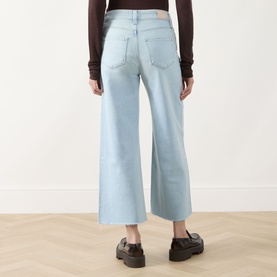 Model wearing Paige straight leg jeans in Motif light blue denim, wide crop cut, styled with black chunky loafers and dark brown top.