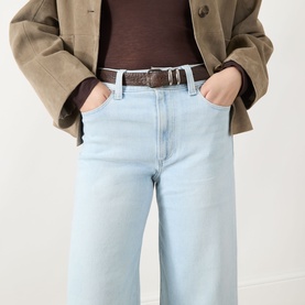 Model wearing Paige Motif straight jeans in light blue denim, styled with a brown belt, dark top and oversized khaki blazer.