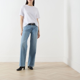 Model wearing Paige Dana Low-Rise Straight Leg Jeans in Sepulveda, wide-leg light blue denim with faded details, styled with white tee and black