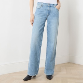 Model wearing Paige Dana Low-Rise Straight Leg Jeans in Sepulveda, light blue wash with whiskering, wide leg, styled with black heeled boots.