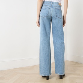 Model wearing Paige Dana Low-Rise Straight Leg Jeans in Sepulveda, rear view showing logo badge, five-pocket style and wide leg fit.