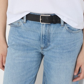 Model wearing Paige Dana Low-Rise Straight Leg Jeans in Sepulveda, light blue wash with whiskering, styled with a white tee and black belt.