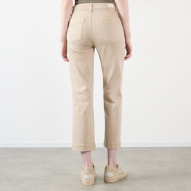 Model wearing Paige Vintage Warm Sand straight jeans, rear view, styled with beige espadrille wedges.