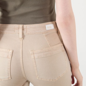 Model wearing Paige Straight Jeans in Vintage Warm Sand, close-up of back pockets, styled with an olive top.