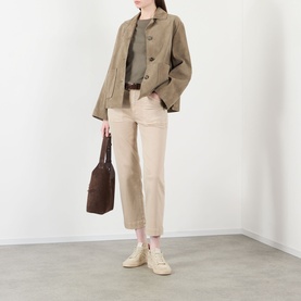 Model wearing Paige Vintage Warm Sand straight jeans, styled with a khaki jacket, olive top and cream trainers, carrying a brown bag.