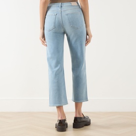 Model wearing Paige straight jeans in Coliseum light blue denim, cropped length, rear view, styled with black chunky loafers.