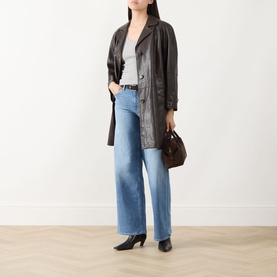 Model wearing Paige Cinerama straight jeans in light blue denim, styled with dark leather coat, grey top and black heels.