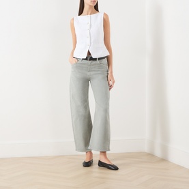 Model wearing Paige Arellia Ankle Wide-Leg Jeans in Vintage Seaglass, styled with a white sleeveless waistcoat and black ballet flats.