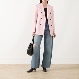 Model wearing Paige Terazzo Deconstructed wide leg jeans with ripped knees, styled with a pink blazer and black heels