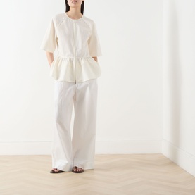Model wearing Samsoe & Samsoe Satoman Peplum Blouse in Egret, styled with wide-leg white trousers and dark brown sandals