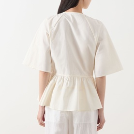 Model wearing Samsoe & Samsoe Satoman Peplum Blouse in Egret, showing back view with flared peplum hem and wide short sleeves.