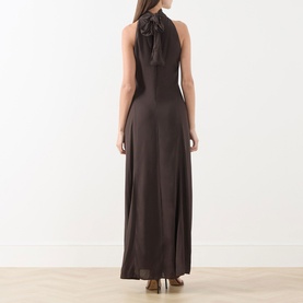 Model wearing Samsoe & Samsoe mulch halterneck maxi dress with bow tie detail, shown from the back, floor-length silhouette