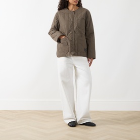 Model wearing Samsoe & Samsoe Major Brown quilted polyamide jacket with white wide-leg trousers and black flat shoes.