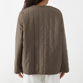 Model wearing Samsoe & Samsoe Major Brown quilted polyamide jacket, rear view, with white trousers visible beneath.