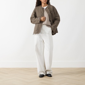 Model wearing Samsoe & Samsoe Major Brown quilted polyamide jacket, styled with cream knit and wide-leg white trousers.
