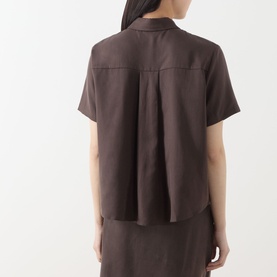 Model wearing Samsoe & Samsoe Mina Fluid Shirt in Mulch, rear view showing box pleat detail, short sleeves, curved hem, styled with matching skirt.
