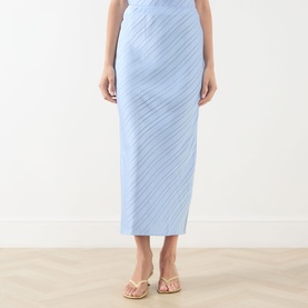 Model wearing Samsoe & Samsoe skirt in Windsurfer blue, featuring diagonal pliss&eacute; texture, midi length, styled with nude strappy sandals.