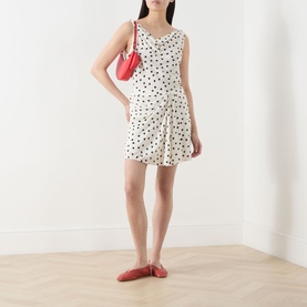 Model wearing Samsoe & Samsoe Saiben Polka Dot Skirt in Drifting Dots Egret, mini length with draped detail, styled with red crossbody bag and red