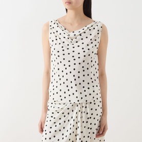 Model wearing Samsoe & Samsoe Sapoppy Polka Dot Top in Drifting Dots Egret, sleeveless with cowl neckline, styled with matching polka dot skirt.
