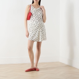 Model wearing Samsoe & Samsoe Sapoppy Polka Dot Top in Drifting Dots Egret, styled with matching shorts, red bag and red flats.