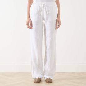 Model wearing Samsoe & Samsoe white linen trousers with drawstring waist, wide-leg fit, styled with tan flat shoes.