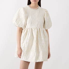 Model wearing Sister Jane Chalk Mini Dress in white jacquard with puff sleeves, styled with a pearl necklace