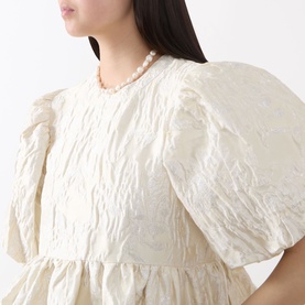 Model wearing Sister Jane Chalk Mini Dress in white jacquard with puff sleeves, styled with a pearl necklace