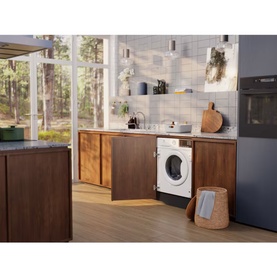Electrolux Built In Washing Machine 8kg 1400 RPM in white, integrated into dark wood kitchen cabinetry, lifestyle setting