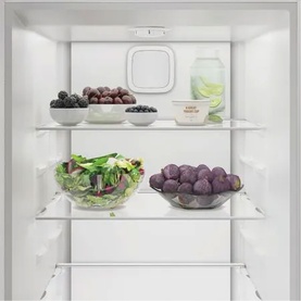 Indesit white fridge interior with three shelves stocked with fresh fruit, salad, and berries in bowls