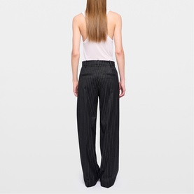 Model wearing Zadig grey pinstripe wide-leg trousers, rear view, styled with a white vest top.
