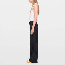 Model wearing Zadig grey wide-leg pinstripe trousers, styled with a white sleeveless top and cream flat shoes, side view.