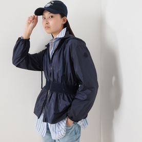 Model with Anine Bing Jeremy Collegiate Logo Cap in blue, styled with a navy zip-up windbreaker jacket and striped shirt.