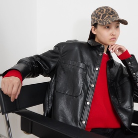 Model with Anine Bing Jeremy Leopard Cap in leopard print, styled with black leather jacket and red knit top.