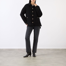 Model wearing Anine Bing black wool-cashmere jacket with gold buttons, styled with grey flared trousers and black heeled ankle boots.