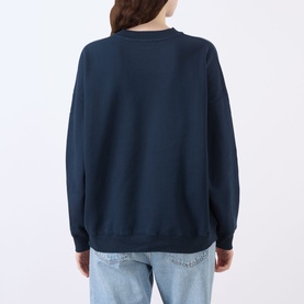 Model wearing Anine Bing Miles Collegiate Logo Sweatshirt in navy, rear view, styled with light blue jeans.