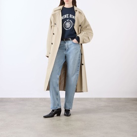 Model wearing Anine Bing Miles Collegiate Logo Sweatshirt in navy, styled with a beige trench coat and light blue straight-leg jeans.