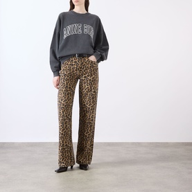 Model wearing Anine Bing Miles Logo Sweatshirt in Washed Black with dropped shoulders, styled with leopard-print wide-leg trousers and black shoes.