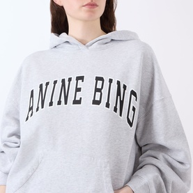 Model wearing Anine Bing Harvey New Classic Hoodie in Grey Melange with bold logo print, kangaroo pocket, and dropped shoulders.