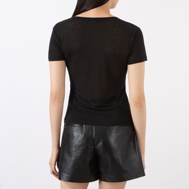 Model wearing Anine Bing black short-sleeve top in lyocell-wool blend, back view, styled with black leather shorts.