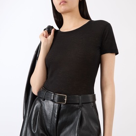 Model wearing Anine Bing black short-sleeve ribbed top, styled with black leather wide-leg trousers and belt.