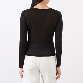 Model wearing Anine Bing black long-sleeve knit top, rear view, styled with white wide-leg trousers.