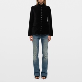 Model wearing Zadig black velvet military-style blazer with button front, styled with light wash flared jeans and black heeled sandals
