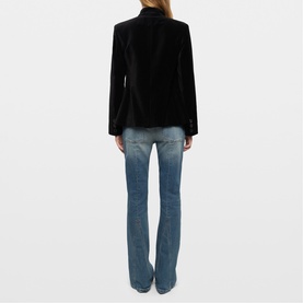 Model wearing Zadig black velvet blazer, back view, styled with mid-wash blue flare jeans.