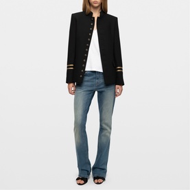 Model wearing Zadig black military-style jacket with gold buttons and stripe cuffs, styled with white tee and light blue flared jeans