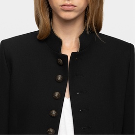 Model wearing Zadig black military-style jacket with dark gold button detail and mandarin collar, styled over white top.