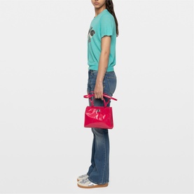 Model carrying a small red Zadig structured top-handle bag with contrast handle detail, styled with teal tee and flared jeans.