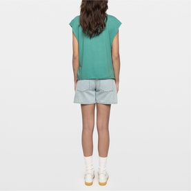 Model wearing Zadig green sleeveless top, styled with light blue denim shorts and white trainers, shot from behind.